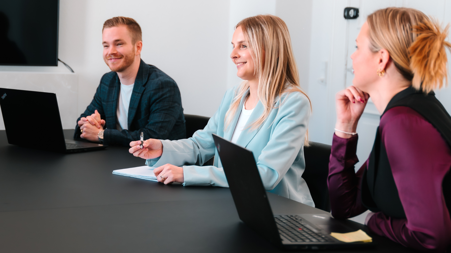 Møde i marketing virksomhed med yngre smilende medarbejdere i blazere